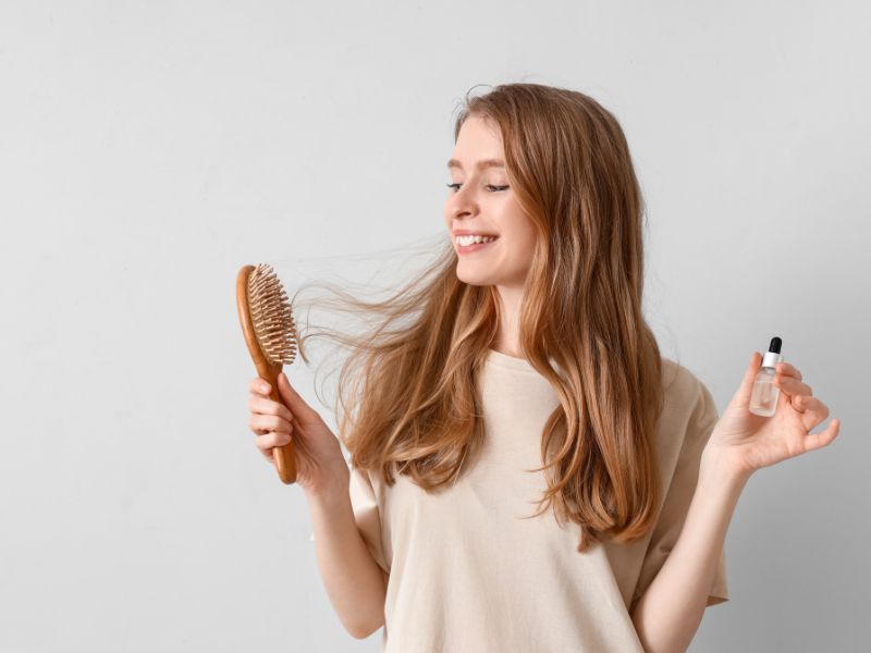 A happy women holding a comb and small bottle